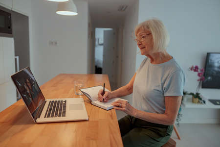 Senior woman using laptop while sitting at homeの写真素材