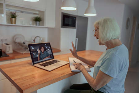 Happy senior woman with laptop computer at homeの写真素材