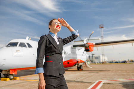 Joyful woman flight attendant standing outdoors at airportの写真素材
