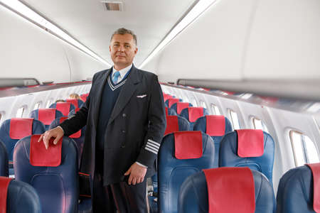 Male airline worker standing in aircraft passenger salonの写真素材