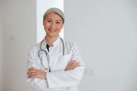 Portrait of attractive mature woman doctor in white coat with stethoscopeの写真素材