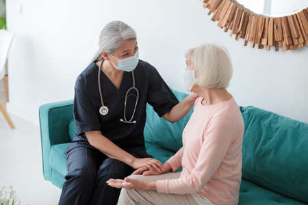 Adult doctor speaking to elderly woman oppositeの写真素材