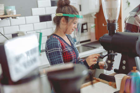 Portrait of focused barista grinding coffee beans in coffee grinderの写真素材