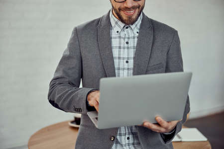 Cheerful young man using laptop in cafeの写真素材