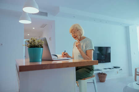 Senior woman looking at laptop screen indoorsの写真素材