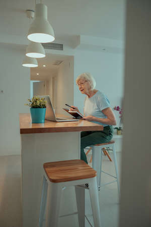 Senior woman sitting at table at homeの写真素材