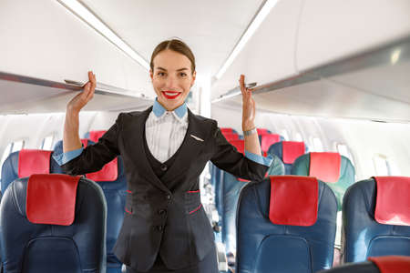 Cheerful stewardess standing in airplane passenger salonの写真素材