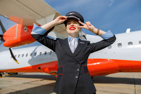Cheerful woman flight attendant standing outdoors at airportの写真素材