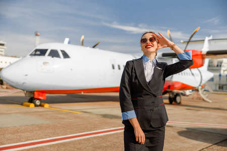 Cheerful woman stewardess standing outdoors at airportの写真素材