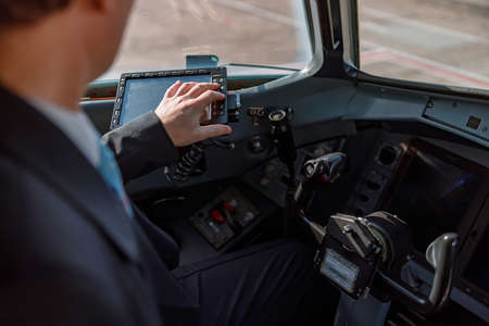 Aircraft pilot sitting in cockpit and using flight displayの写真素材