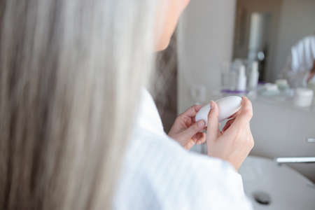 Close-up photo of soft woman hands holding cosmetic jarの写真素材