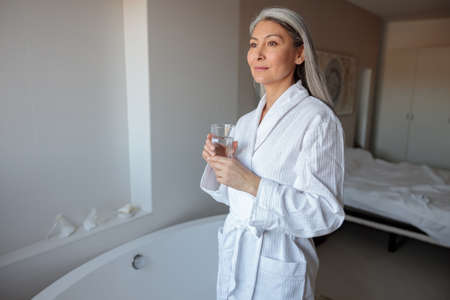 Woman drinking water in the morning in hotel roomの写真素材