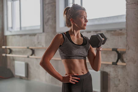 Sporty female athlete lifting dumbbell in gymの写真素材