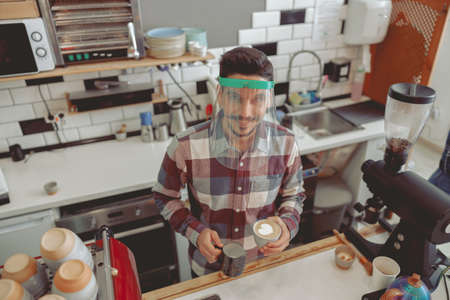 Portrait of barista making pattern of frothed milkの写真素材