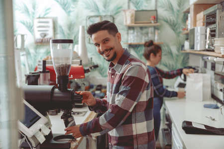 Man barista working in coffee shop near coffee grinderの写真素材