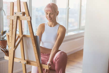 Attractive positive lady artist at work upon new picture at homeの写真素材