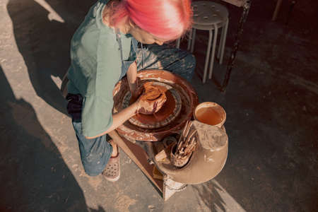 Young female artisan concentrated on modeling clay in workroomの写真素材