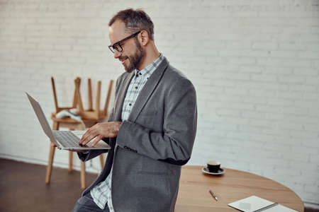 Bearded man using modern laptop in cafeの写真素材
