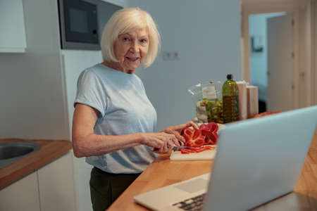 Pensioner female cooking in kitchen at homeの写真素材