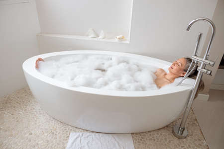 Lady lying in the bathtube in the bathroomの写真素材