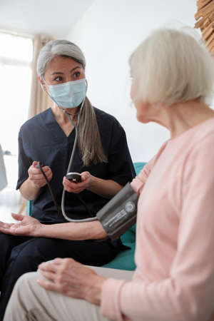 Medical worker examining elderly female at homeの写真素材