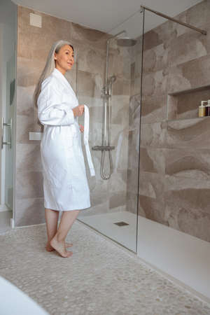 Full-length of charming woman in bathrobe preparing to take bathの写真素材