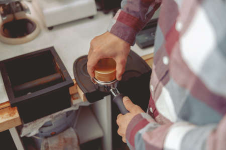 Barista pressing ground coffee into portafilter with tamperの写真素材