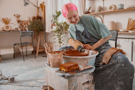 Young female master working with clay in pottery roomの写真素材