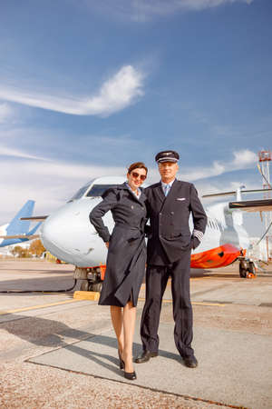 Airplane pilot and stewardess standing outdoors at airportの写真素材