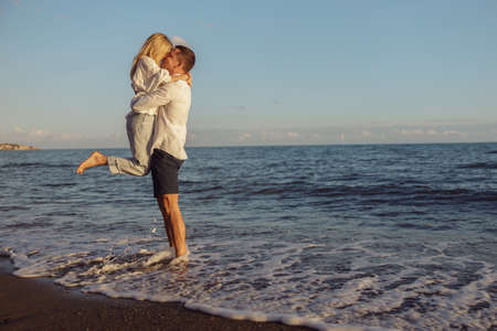 Full length photo man and woman standing on coast and kissingの写真素材