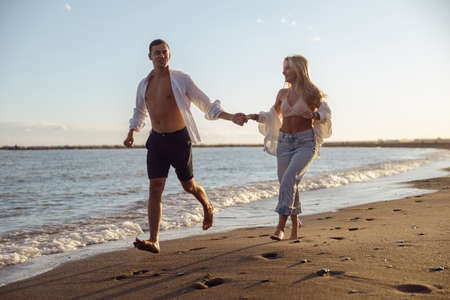 Woman and man walking along the seashore in the eveningの写真素材