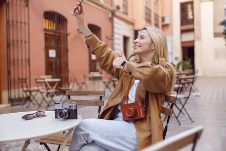 Woman taking selfie on smartphone sitting outsideの写真素材