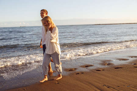 Man and woman walking along the sandy beachの写真素材