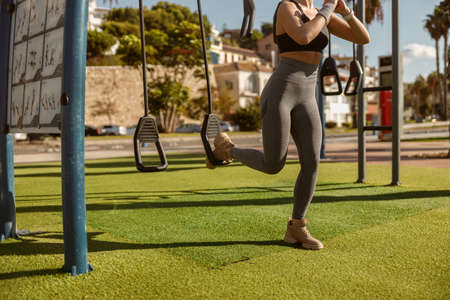 Athletic woman training on exercise equipment at parkの写真素材