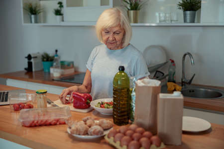 Senior female making salad at home kitchenの写真素材
