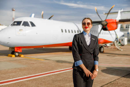 Young woman stewardess standing outdoors at airportの写真素材