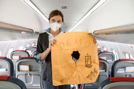 Female flight attendant in medial mask holding life vestの写真素材