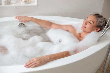 Adult lady lying in the bathtube in spaの写真素材