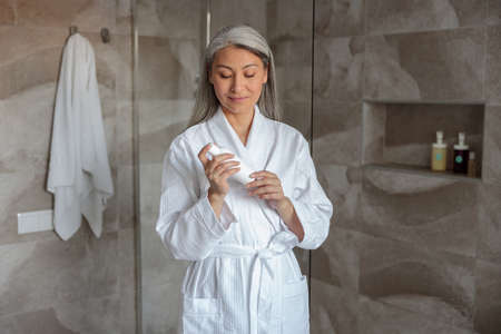 Pretty female preparing to take shower standing in bathroomの写真素材
