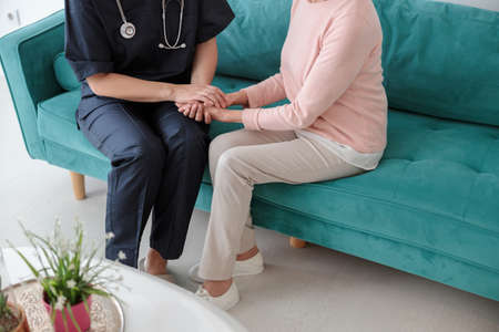 Adult pediatrician visiting old woman at homeの写真素材