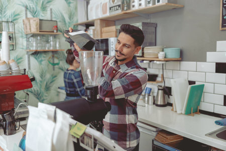 Process of pouring coffee beans into the grinderの写真素材
