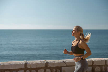 Caucasian young woman exercising near beautiful coastの写真素材