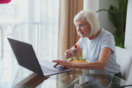 Elderly lady using laptop while sitting at homeの写真素材