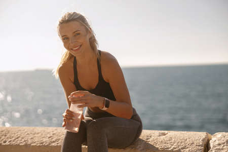 Beautiful young woman resting after workout at natureの写真素材