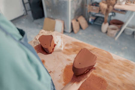 Woman ceramist sculpting raw clay in art studioの写真素材