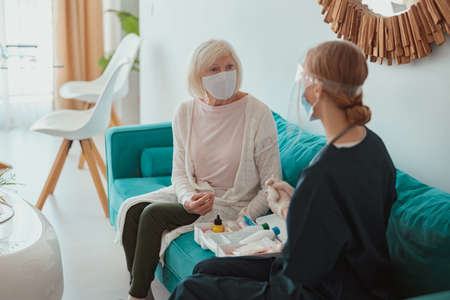 Young nurse examining elderly patient at homeの写真素材