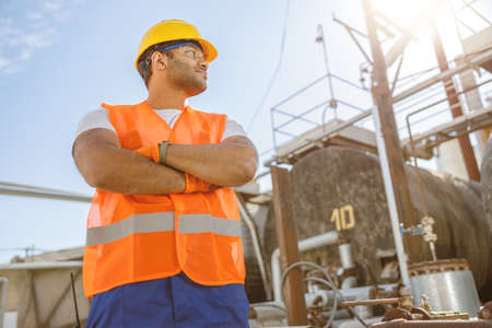 Confident young worker standing at industrial siteの写真素材