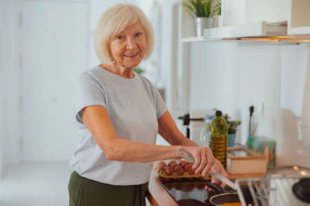 Aged woman cooking food in kitchen at homeの写真素材