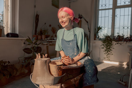 Cute female master working with clay in pottery roomの写真素材