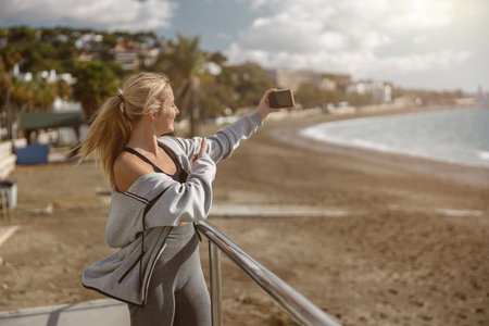 Standing young fit sportswoman watching beautiful seaの写真素材